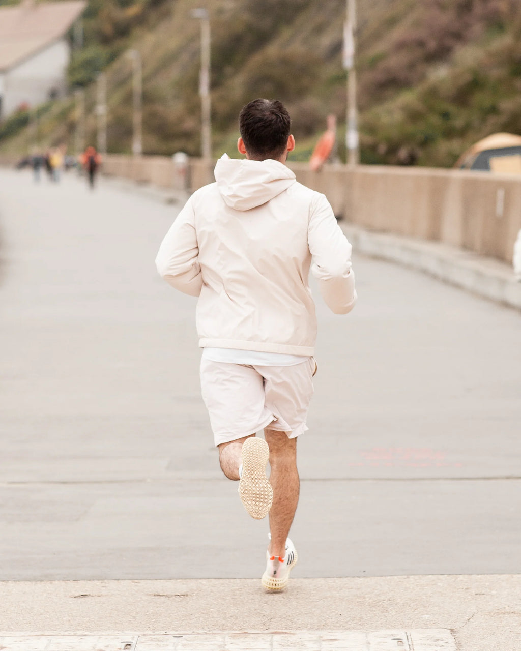 Person running on a road with a scenic background wearing tan coloured sportswear