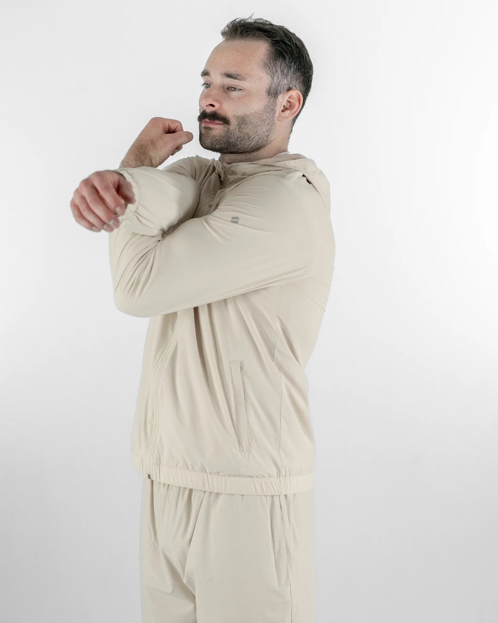 Man wearing a beige sports tracksuit against a white background