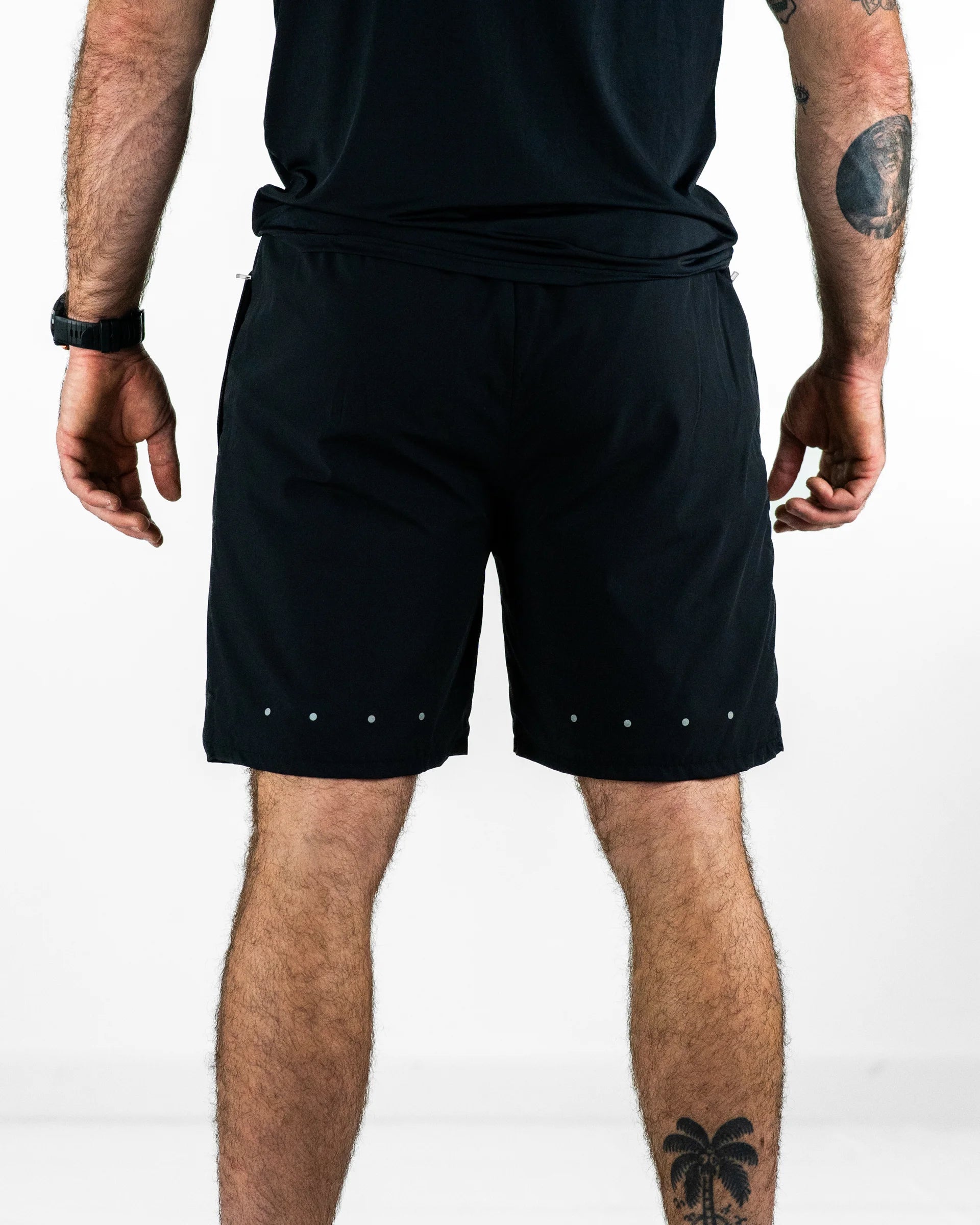 Person wearing black shorts with reflective dots on a white background