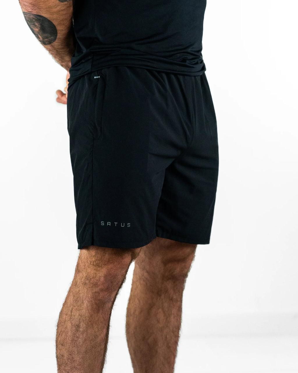 Person wearing black shorts with a visible brand logo on a white background
