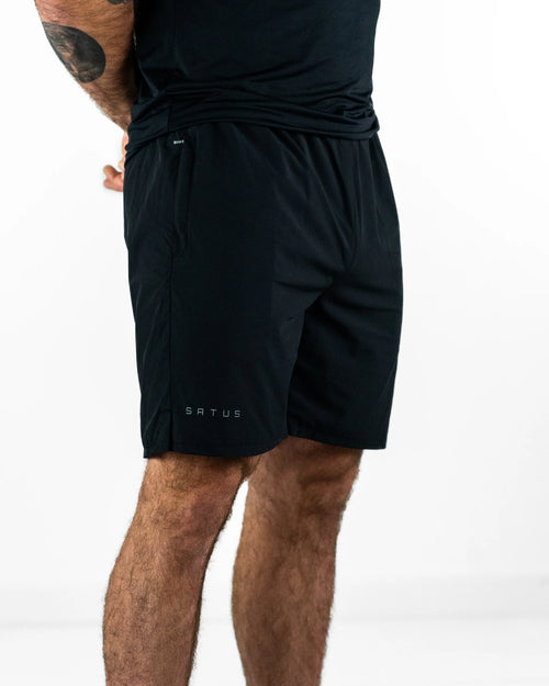 Person wearing black shorts with a visible brand logo on a white background