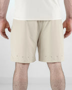 Beige shorts with reflective dots worn by a person on a white background