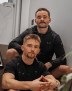 Founders of Satus sitting together in a casual setting, wearing black athletic clothing.