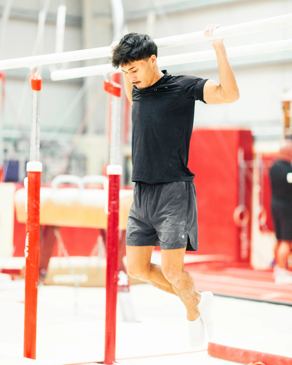Person exercising on parallel bars in a gym setting doing pull ups