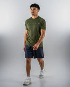 Man wearing a green athletic shirt and black shorts on a gray background