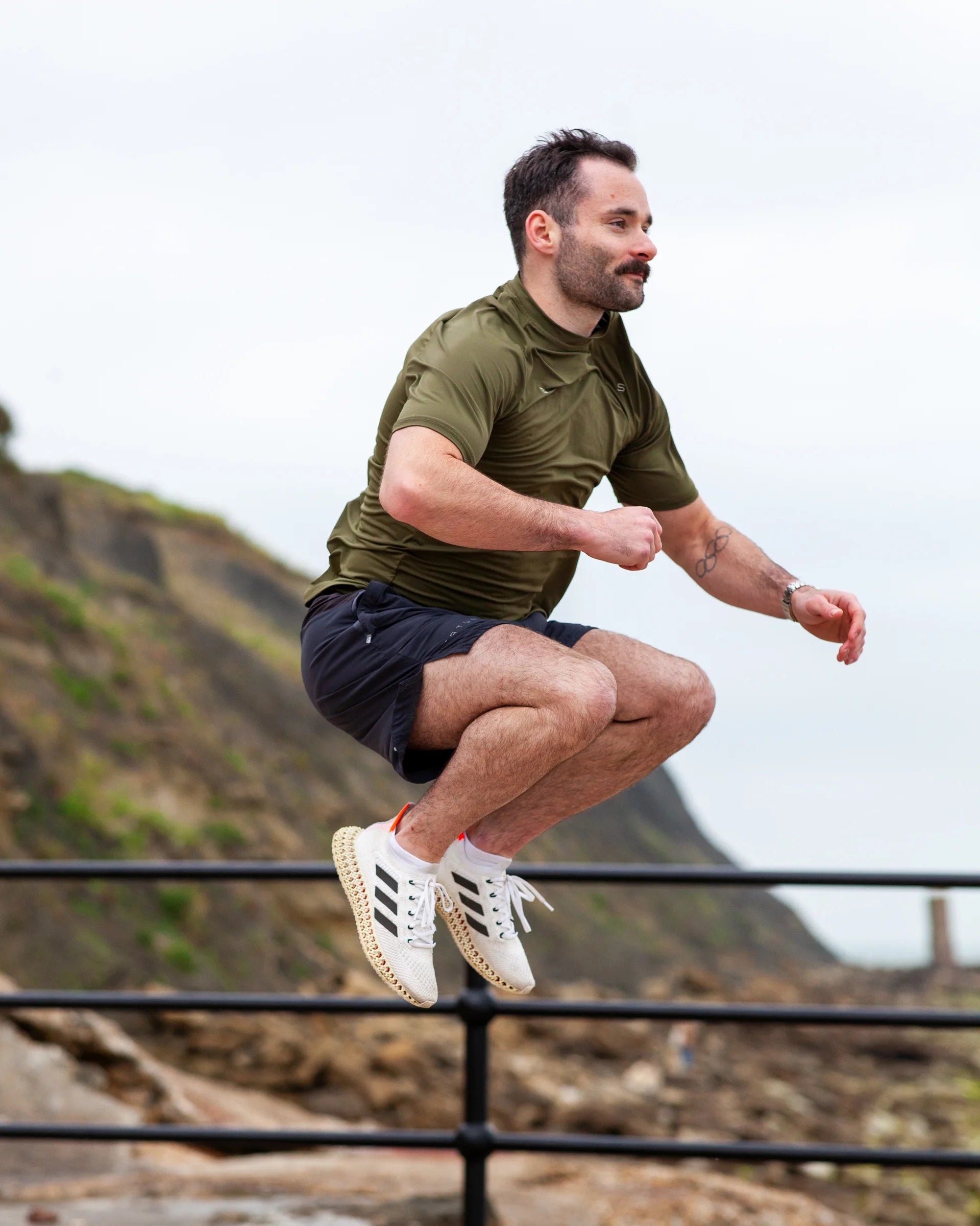 Man in athletic wear jumping outdoors with a scenic background