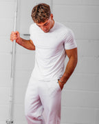 Man wearing a white athletic t-shirt and joggers against a light gray background