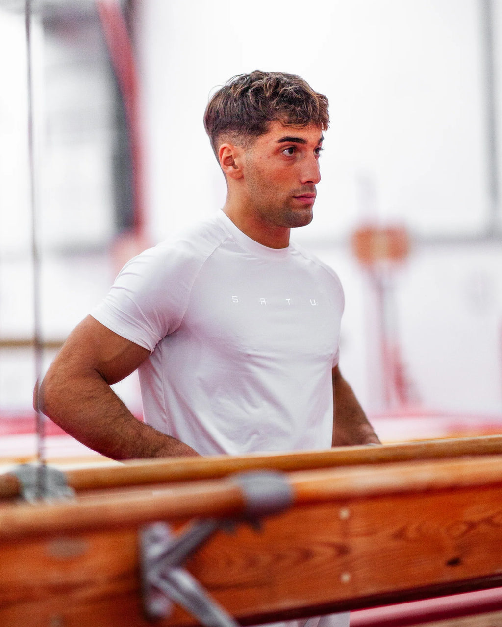 Man in a white t-shirt looking in a mirror in a gym