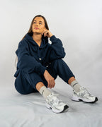 Person wearing a navy tracksuit with white sneakers on a plain background