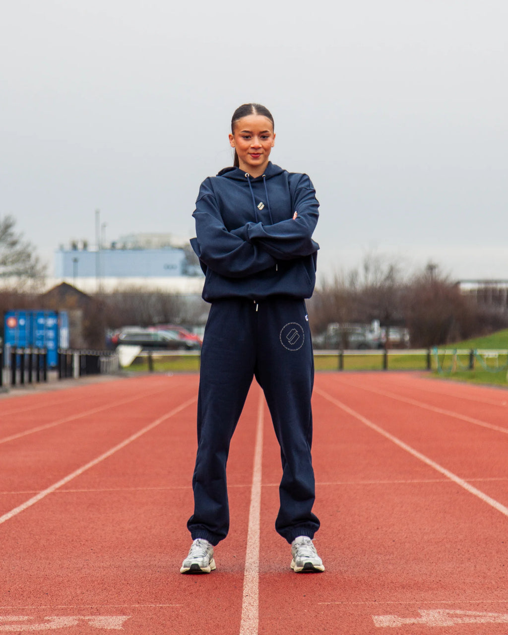 Person wearing a navy tracksuit standing on a running track