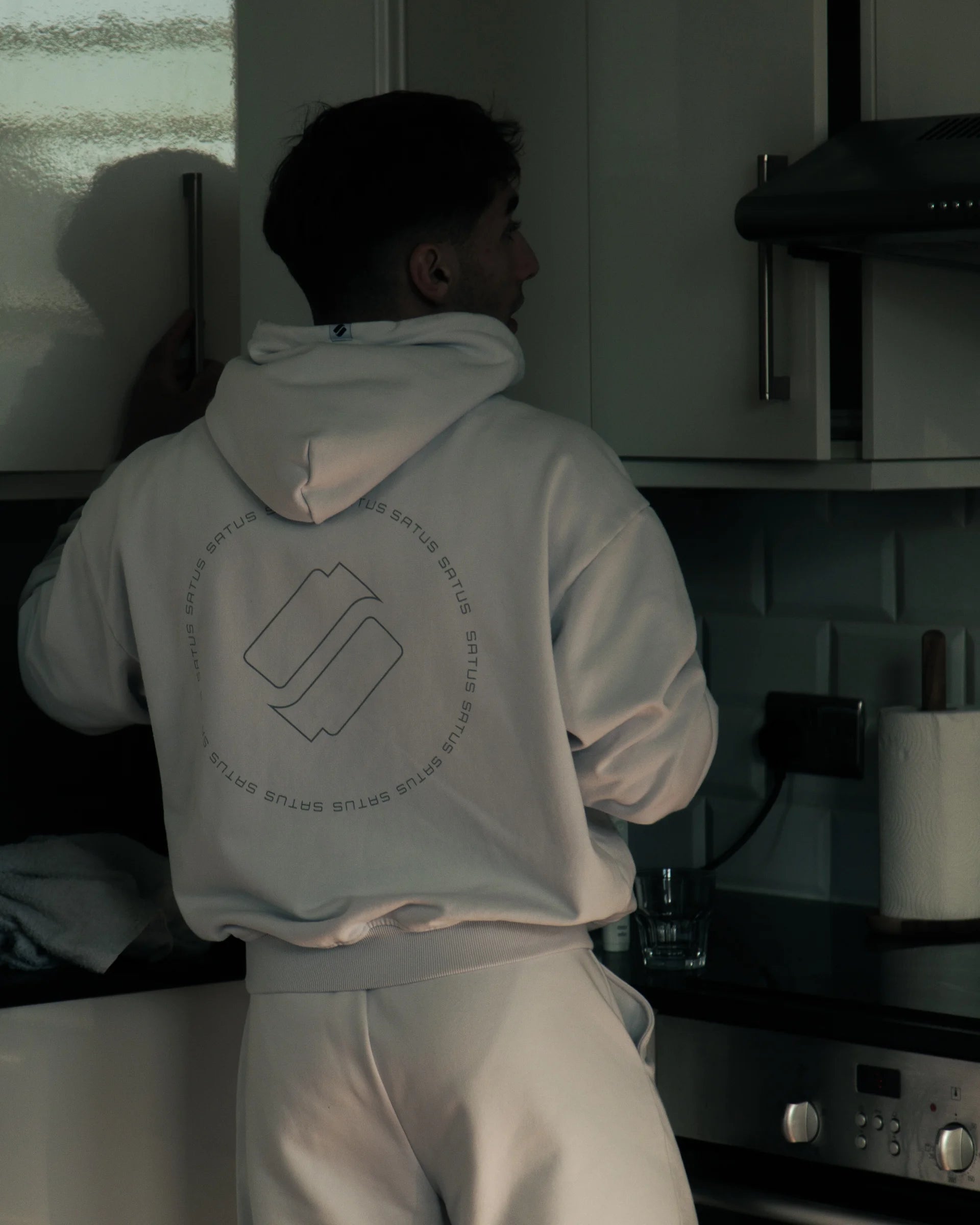 Person wearing a light gray hoodie with a logo in an aestheitc kitchen
