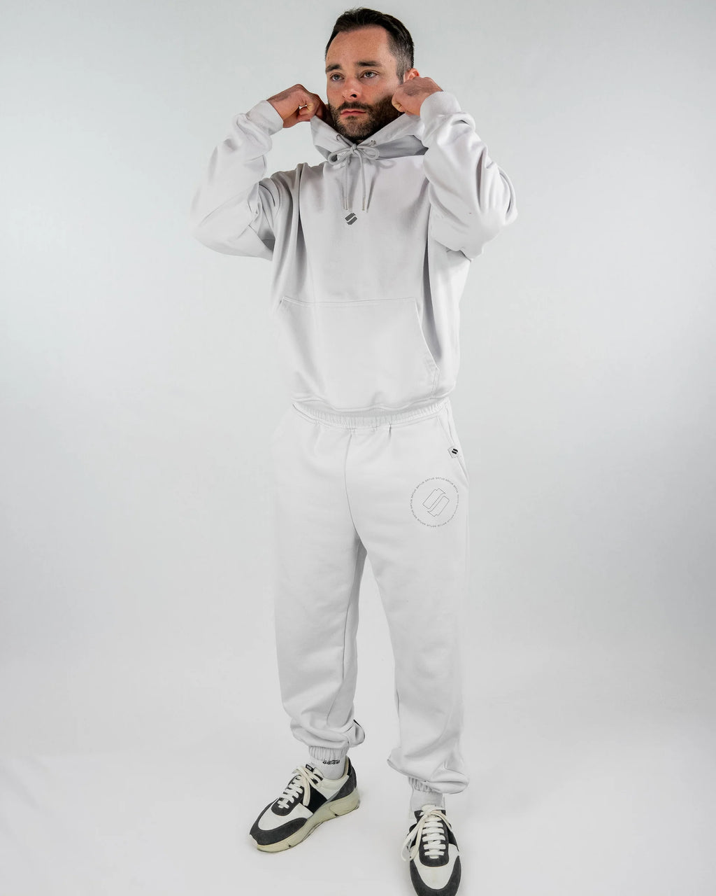Man wearing a gray tracksuit with a brand logo on a white background