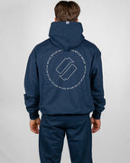 Person wearing a navy blue hoodie with a logo on the back against a light gray background