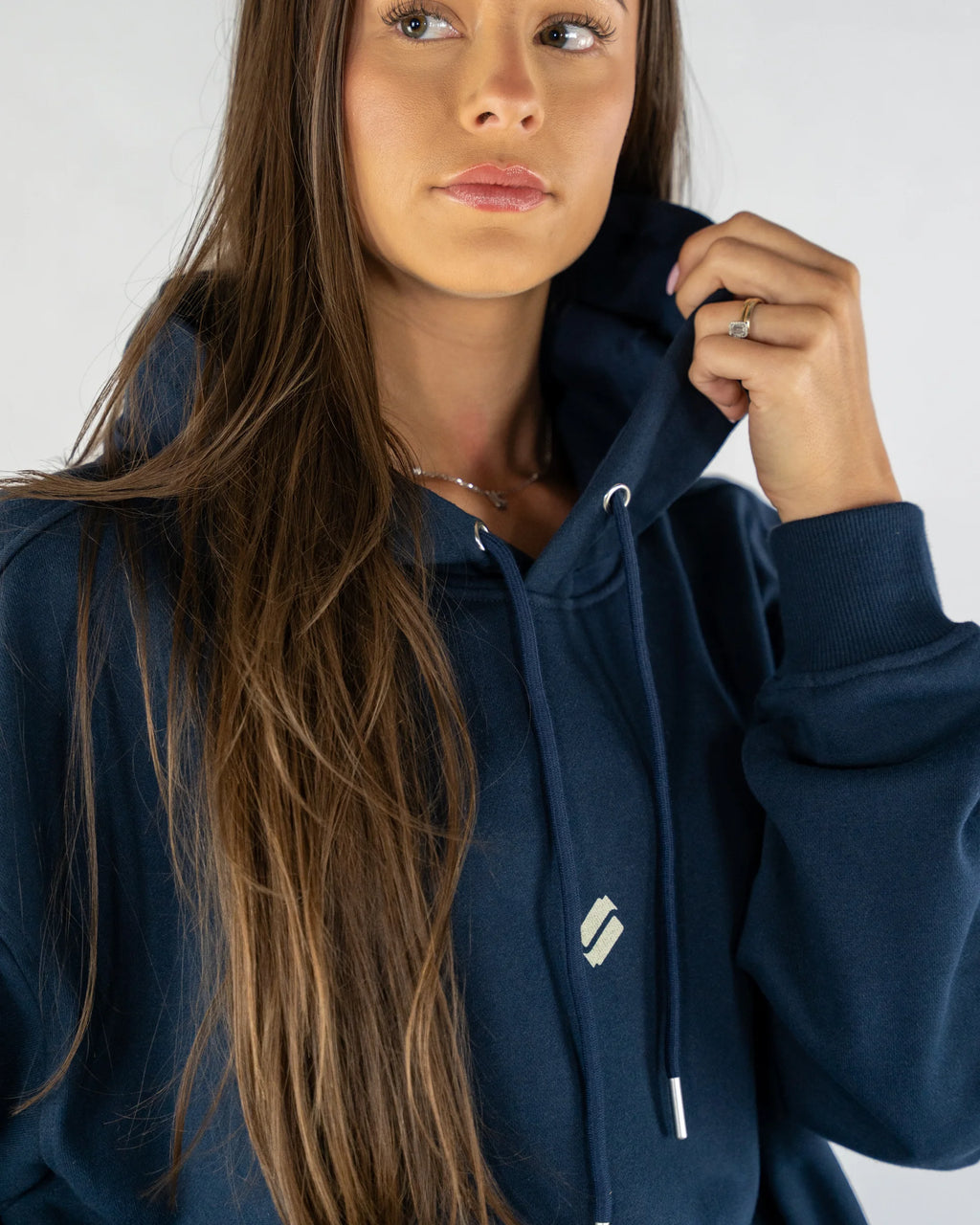 Woman wearing a navy blue hoodie with a logo on a white background