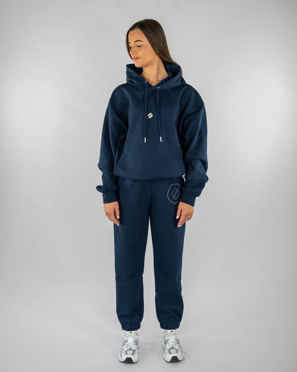Person wearing a navy blue tracksuit on a gray background