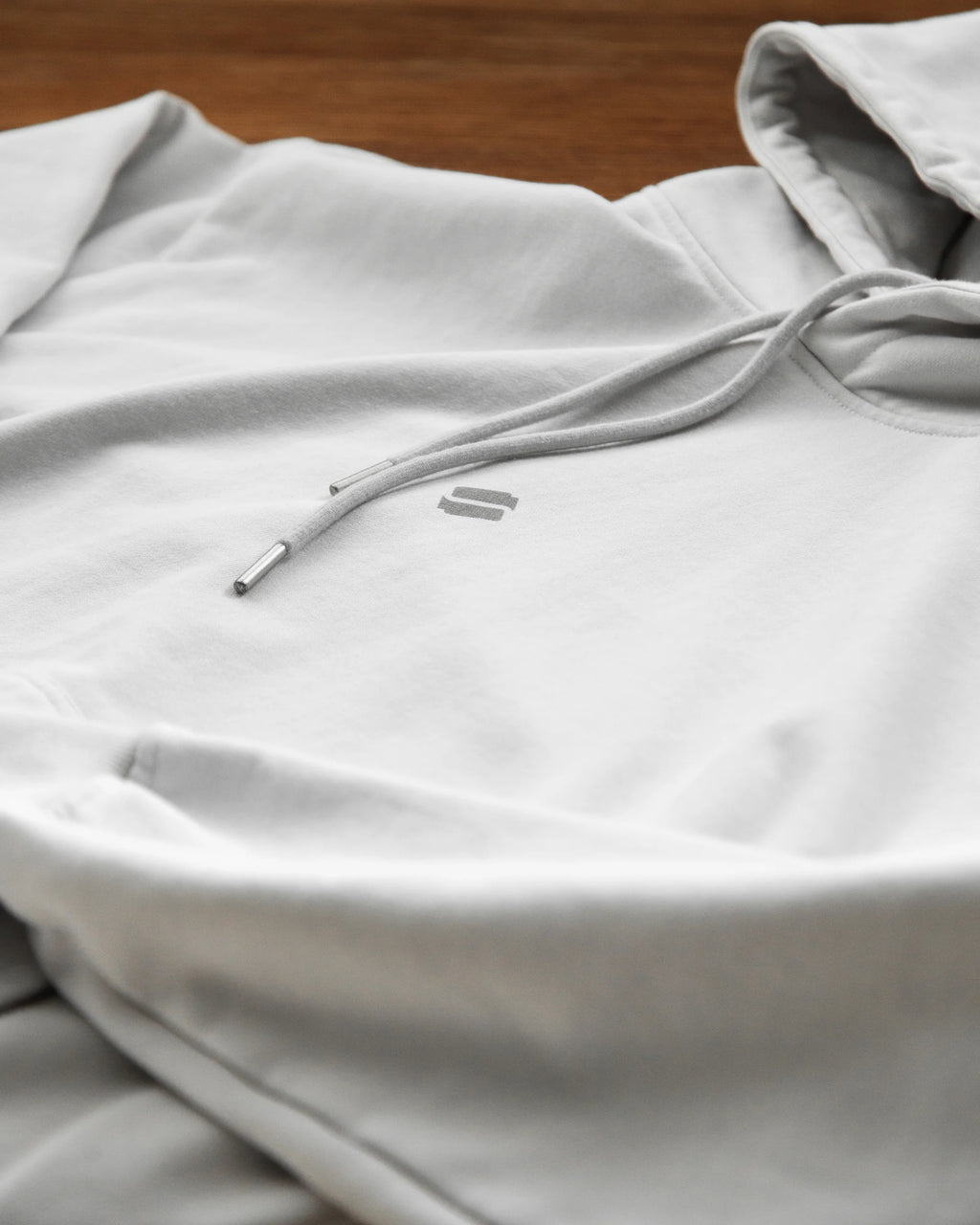 Gray hoodie with drawstring on a wooden surface