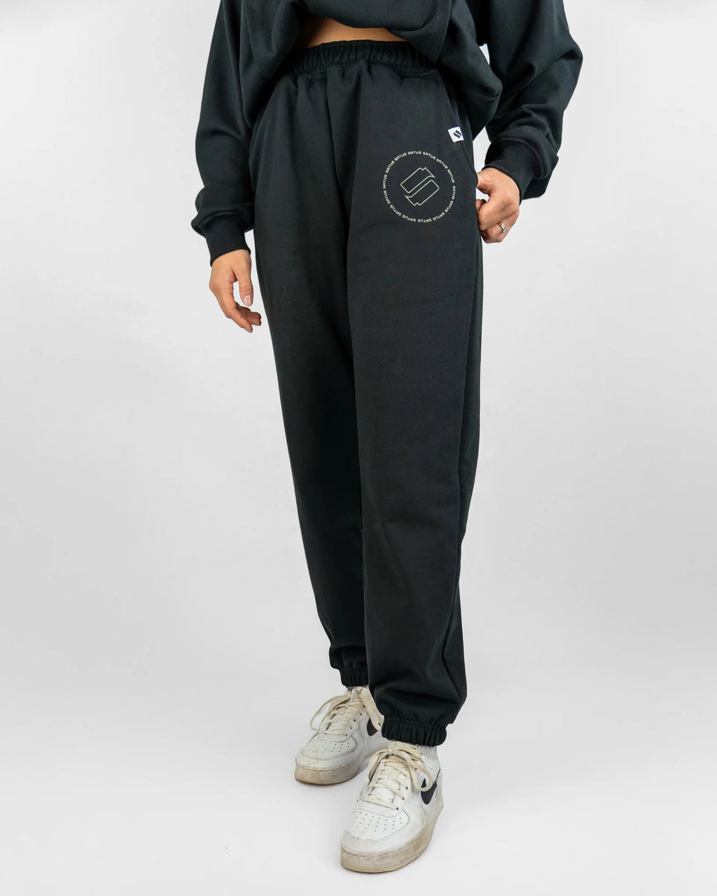 Person wearing black sweatpants with a logo on a white background