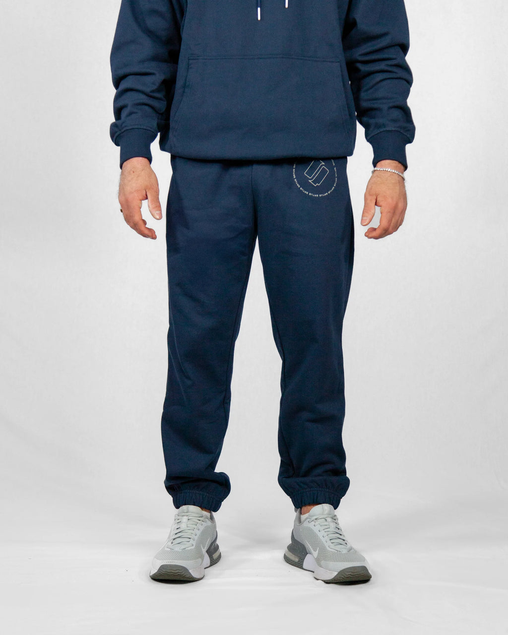 Person wearing a navy tracksuit with a logo on a white background