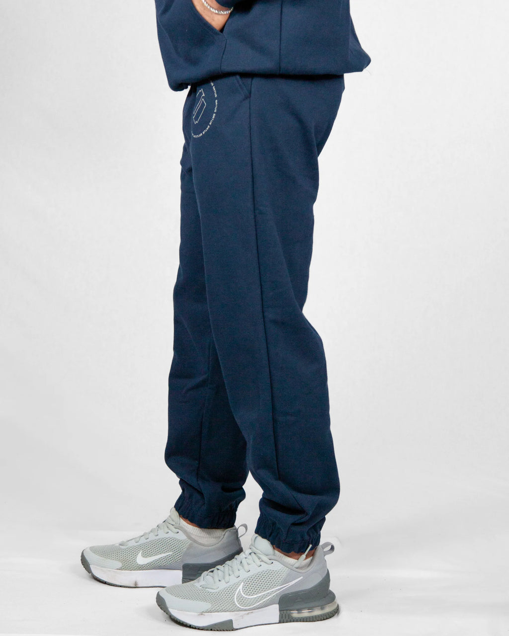 Navy blue jogger pants worn by a person on a white background