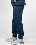 Navy blue jogger pants worn by a person on a white background