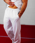 Man wearing light grey joggers with a red and gray background