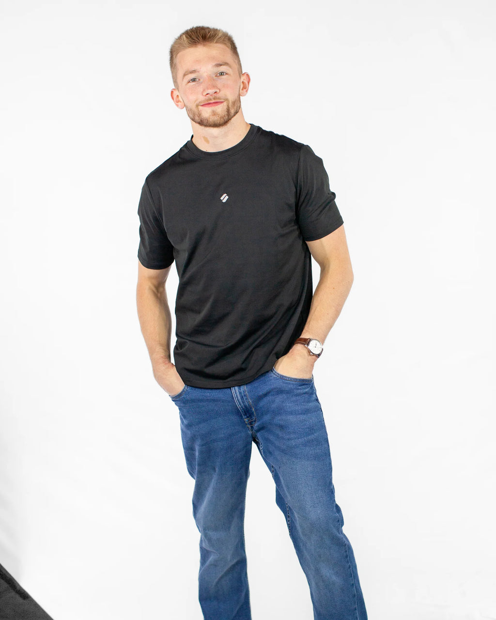 Man wearing a black sports t-shirt and blue jeans on a white background