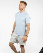 Man wearing a light blue t-shirt and beige shorts on a white background