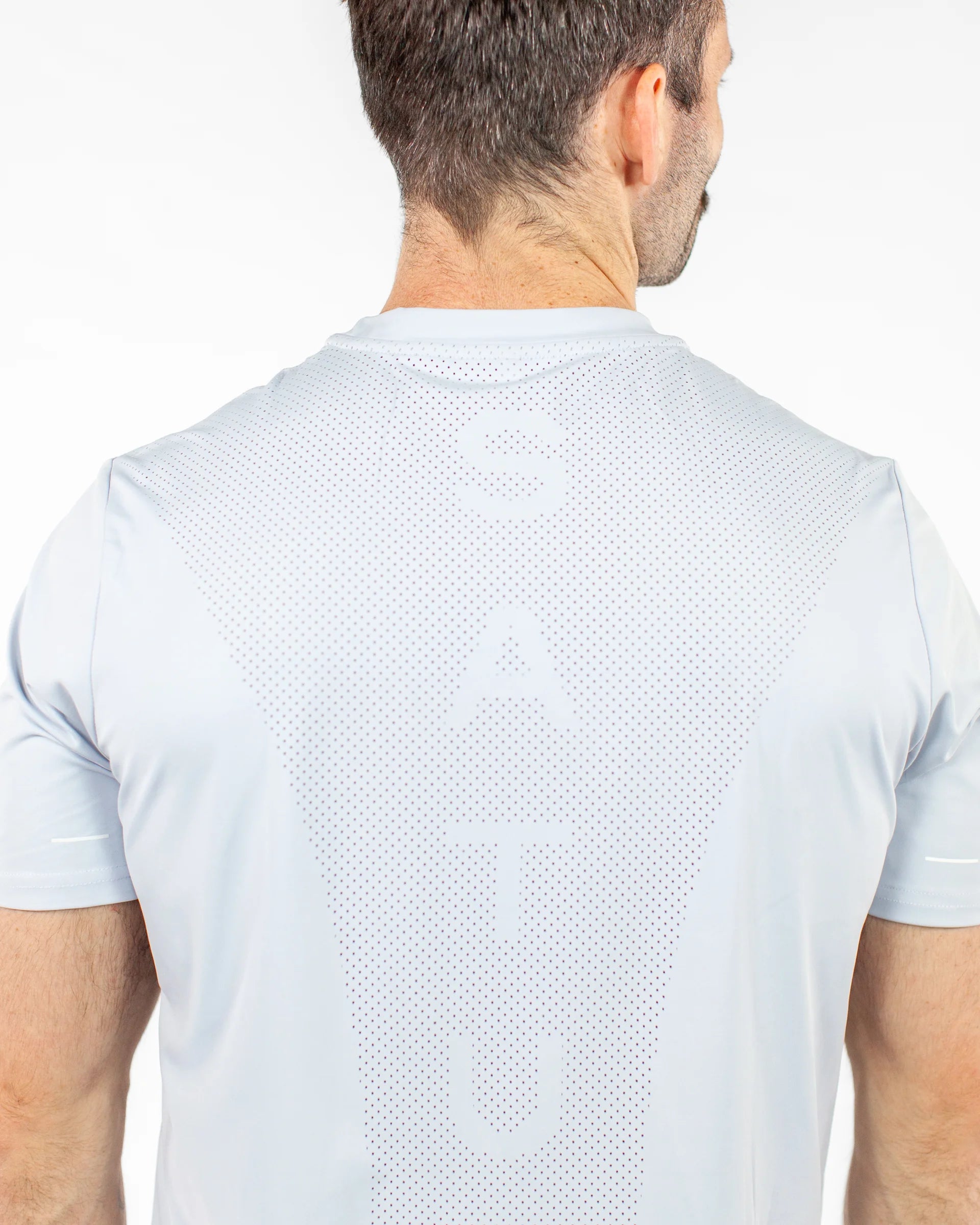 Man wearing a blue athletic shirt with a perforated section on the back on a white background