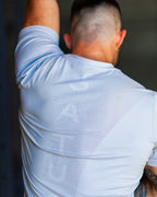 Person wearing a light blue athletic shirt with a brand logo stretching before a crossfit workout