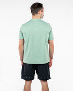 Man wearing a green athletic t-shirt and black shorts on a white background