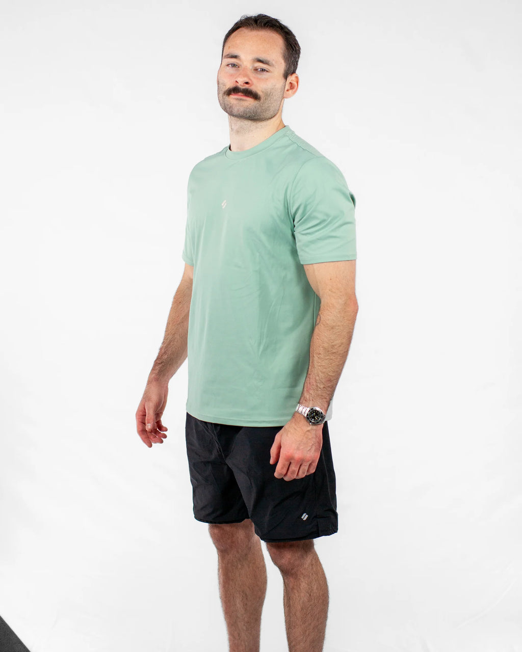Man wearing a green sports t-shirt and black shorts on a white background