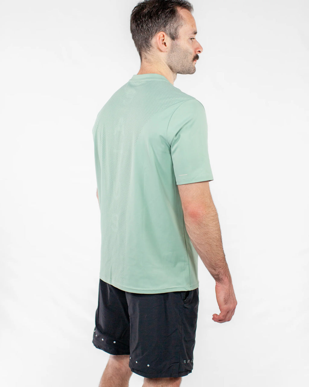 Man wearing a green sports t-shirt and black shorts on a white background