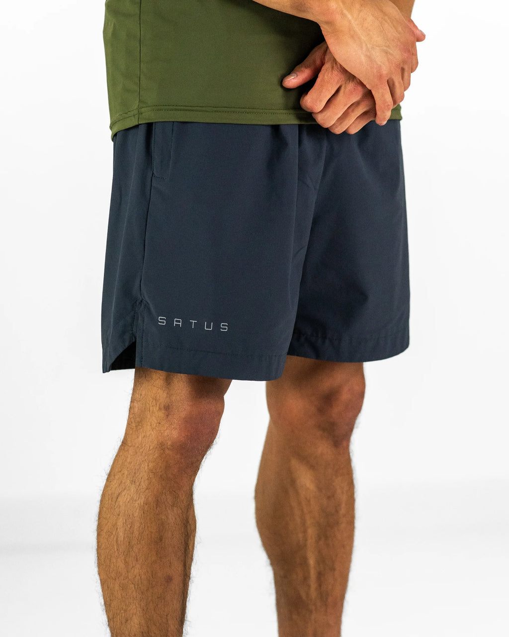 Man wearing dark grey training shorts with a brand logo on a white background