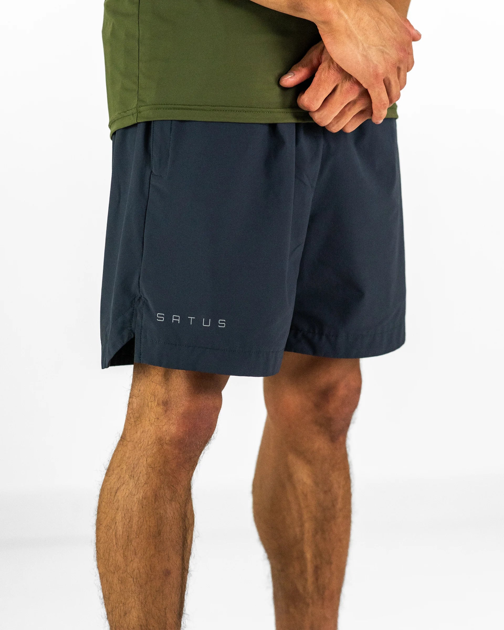 Man wearing dark grey training shorts with a brand logo on a white background