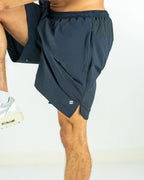 Closeup of the sidesplit of dark grey training shorts worn by a person on a white background